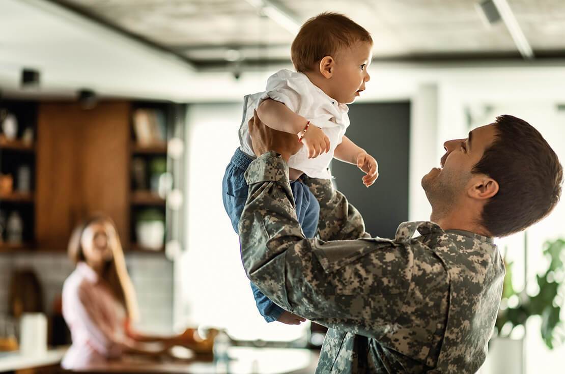 Happy military officer having fun with his baby son at home